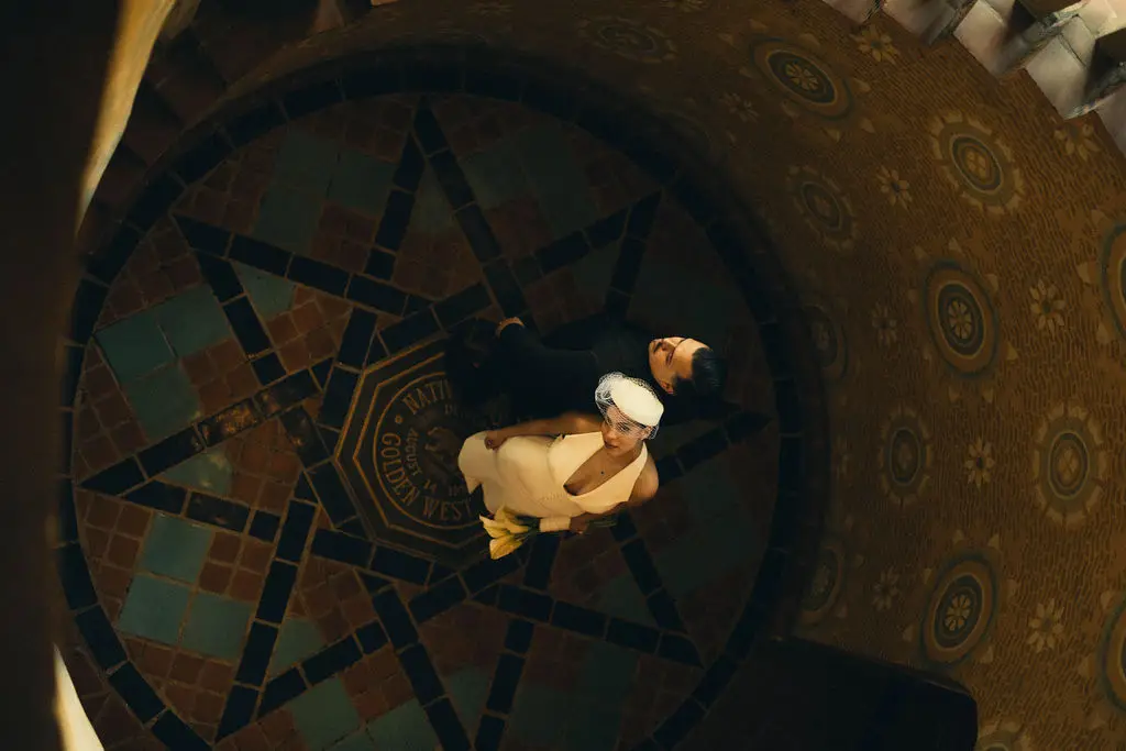 Overhead view of a couple standing on an ornate tiled star medallion inside a grand hall