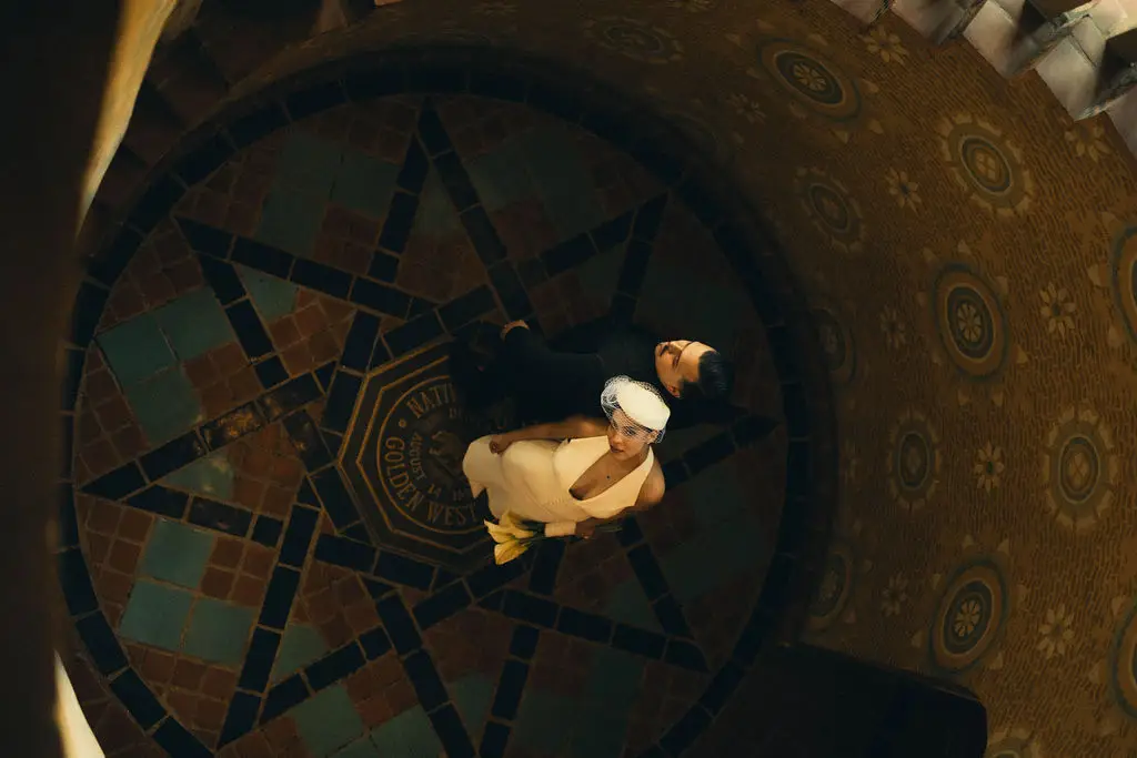 Overhead view of a couple standing on an ornate tiled star medallion inside a grand hall
