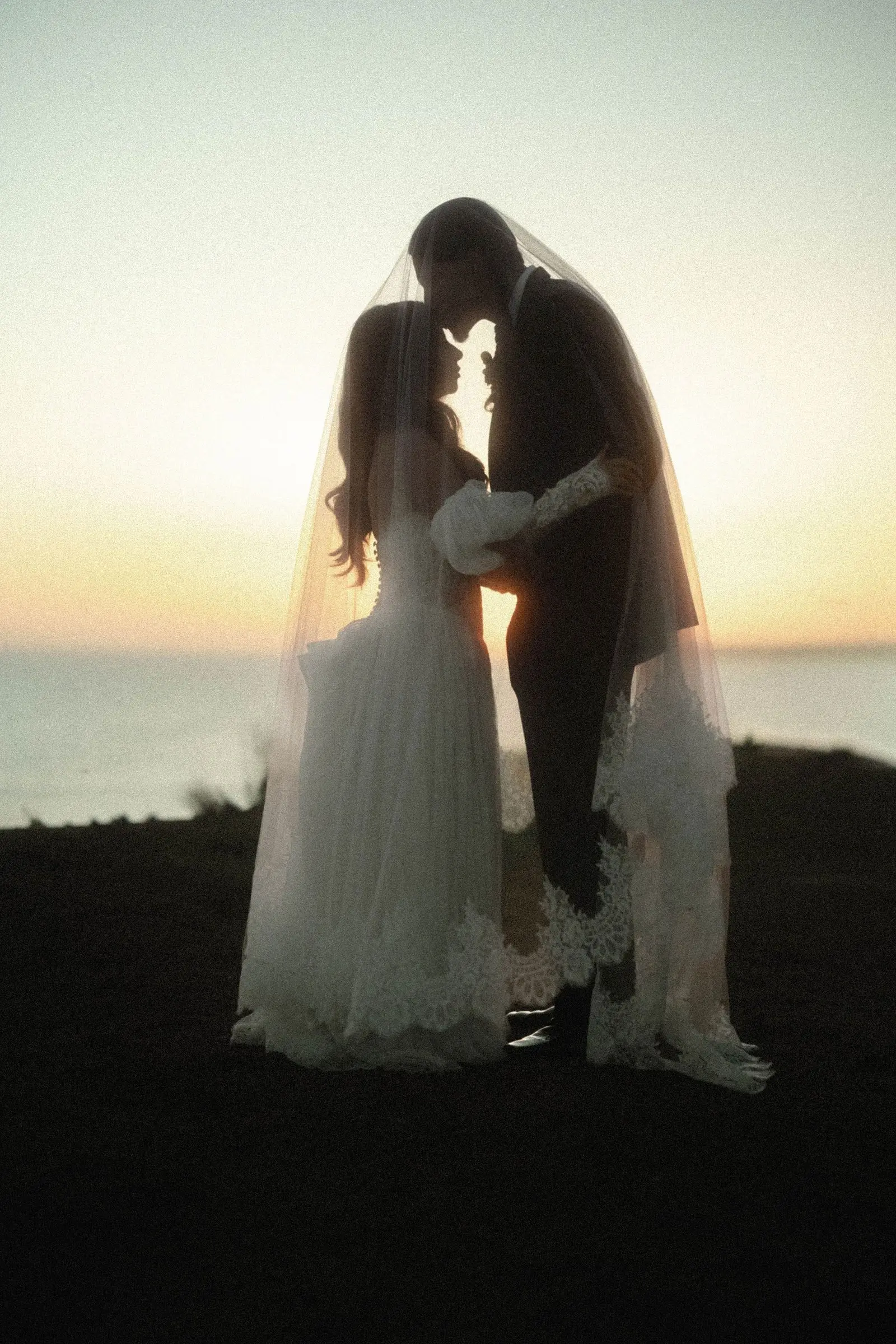 Bride and groom touch foreheads during sunset portraits on the ocean-view bluffs at Casa Romantica in San Clemente, California.