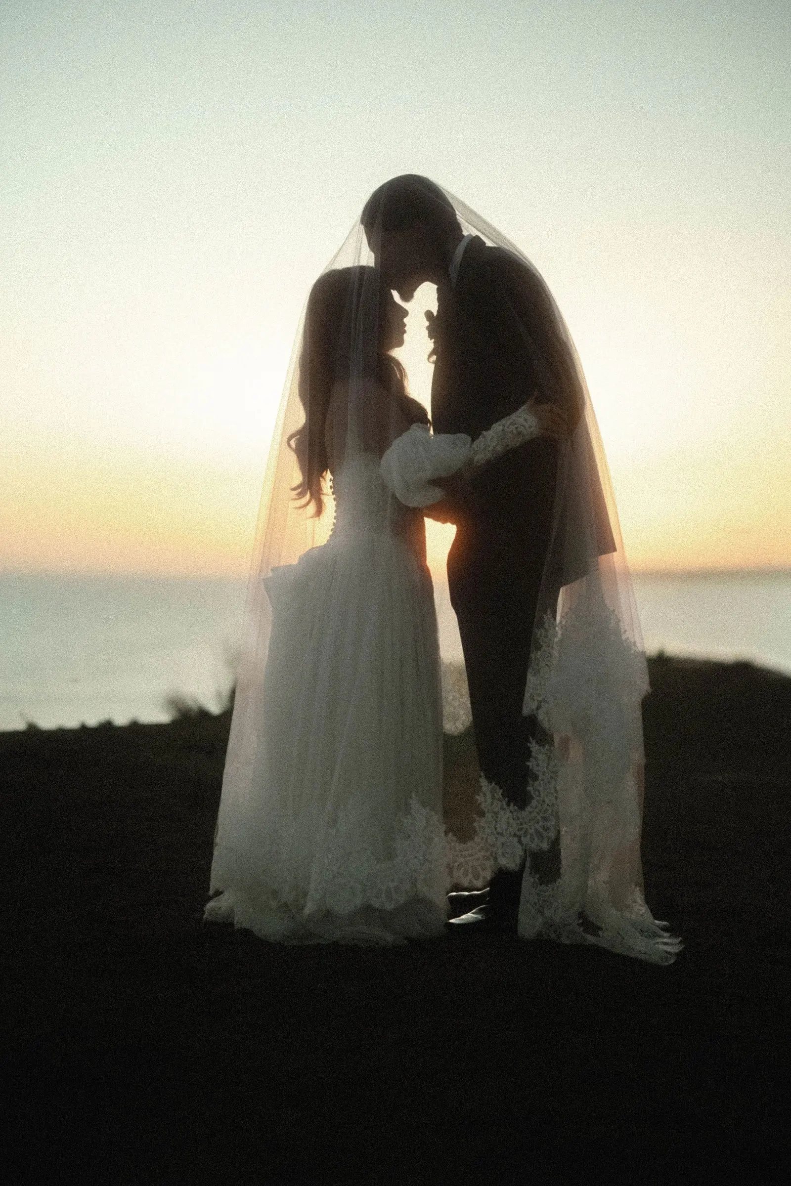 Bride and groom touch foreheads during sunset portraits on the ocean-view bluffs at Casa Romantica in San Clemente, California.