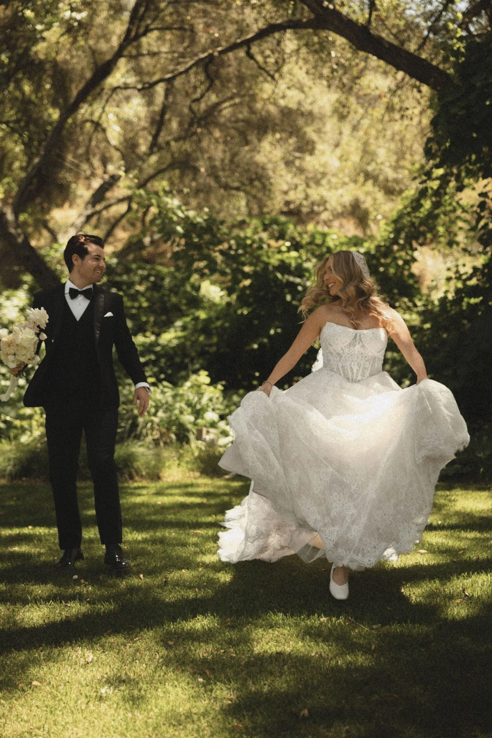 Bride laughing as she runs across the lawn beneath the oak trees at Havens Country Club, her gown catching the light.